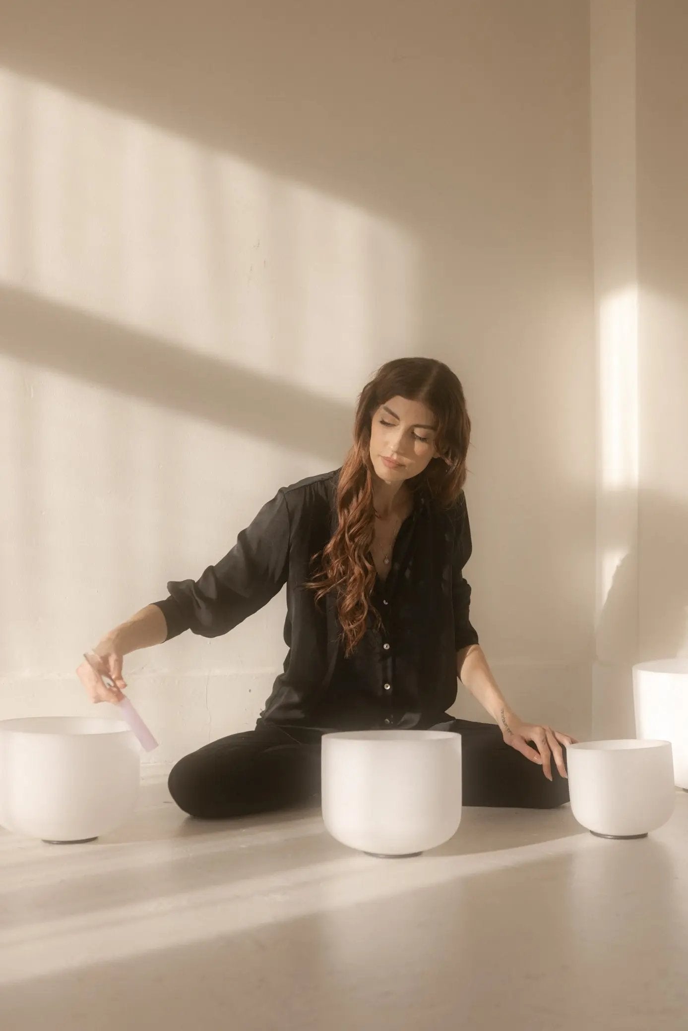 Kasia sitting on the floor with three white containers in a minimalistic setting